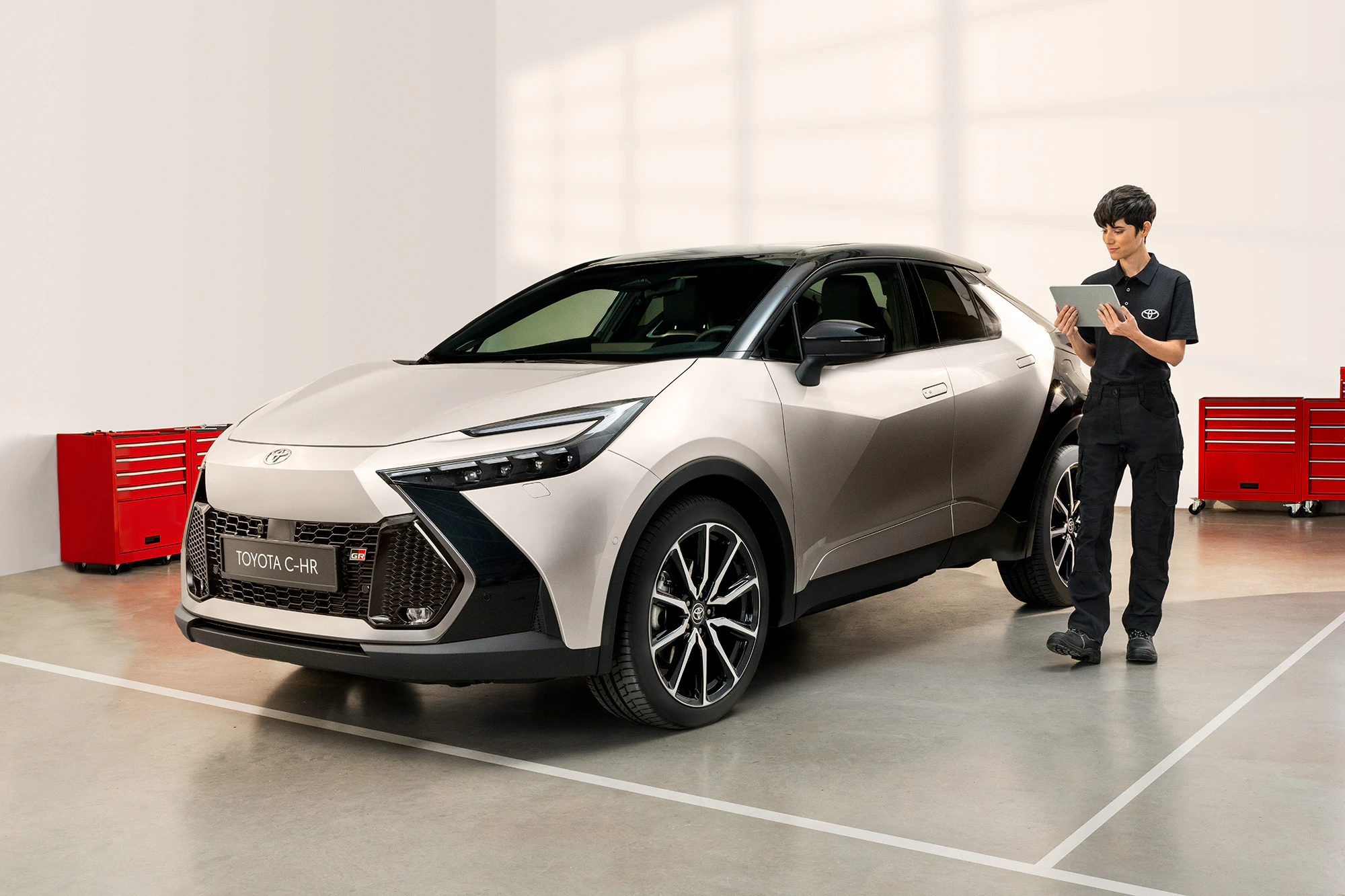 En kvinnlig servicetekniker som står bredvid en vit Toyota i en serviceverkstad