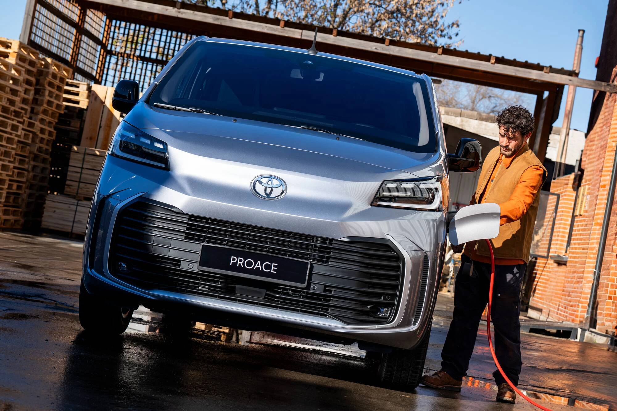 Proace Electric framifrån, en man håller på att ladda