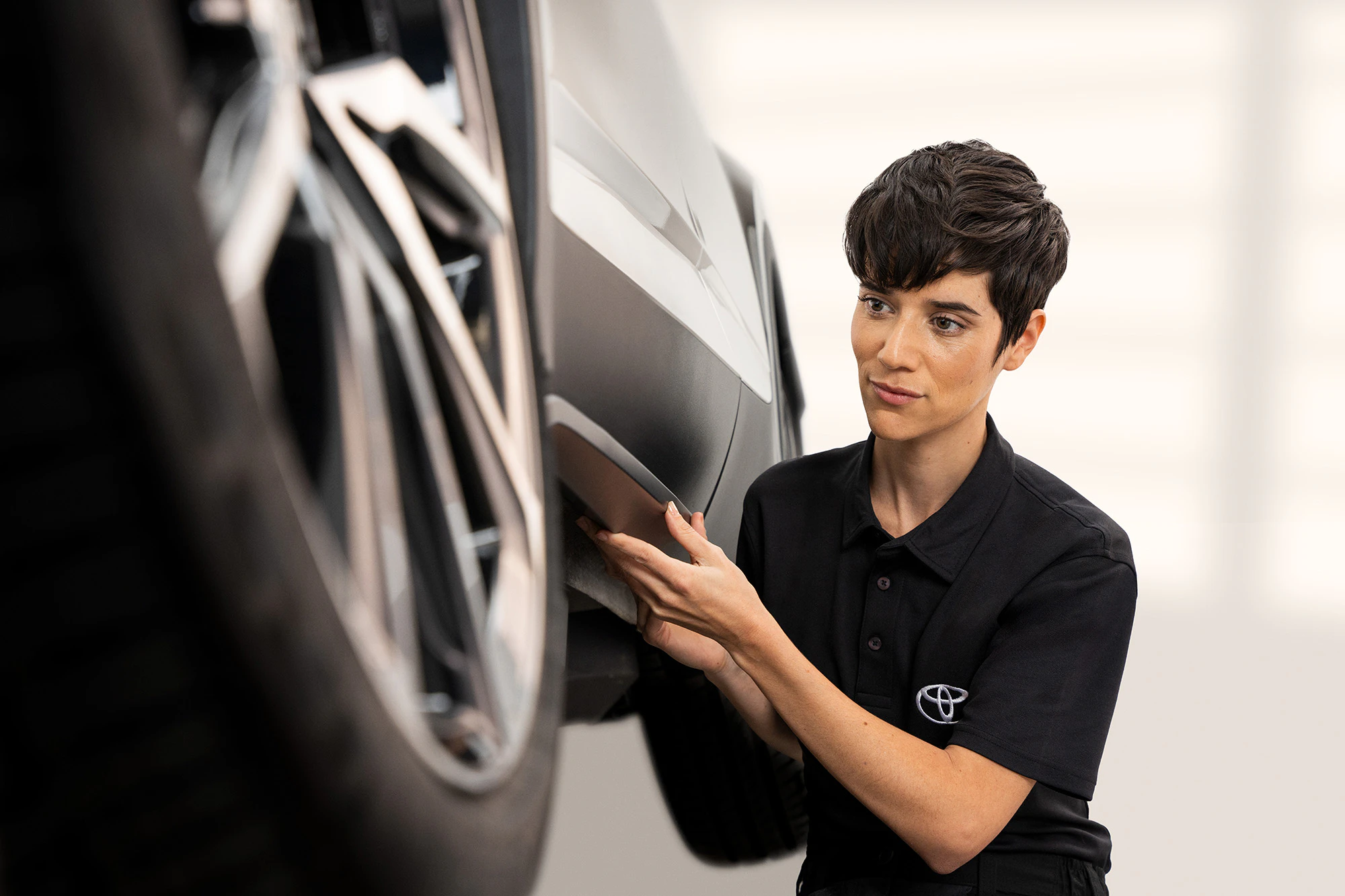 En kvinnlig servicetekniker som granskar ett däck på en Toyota