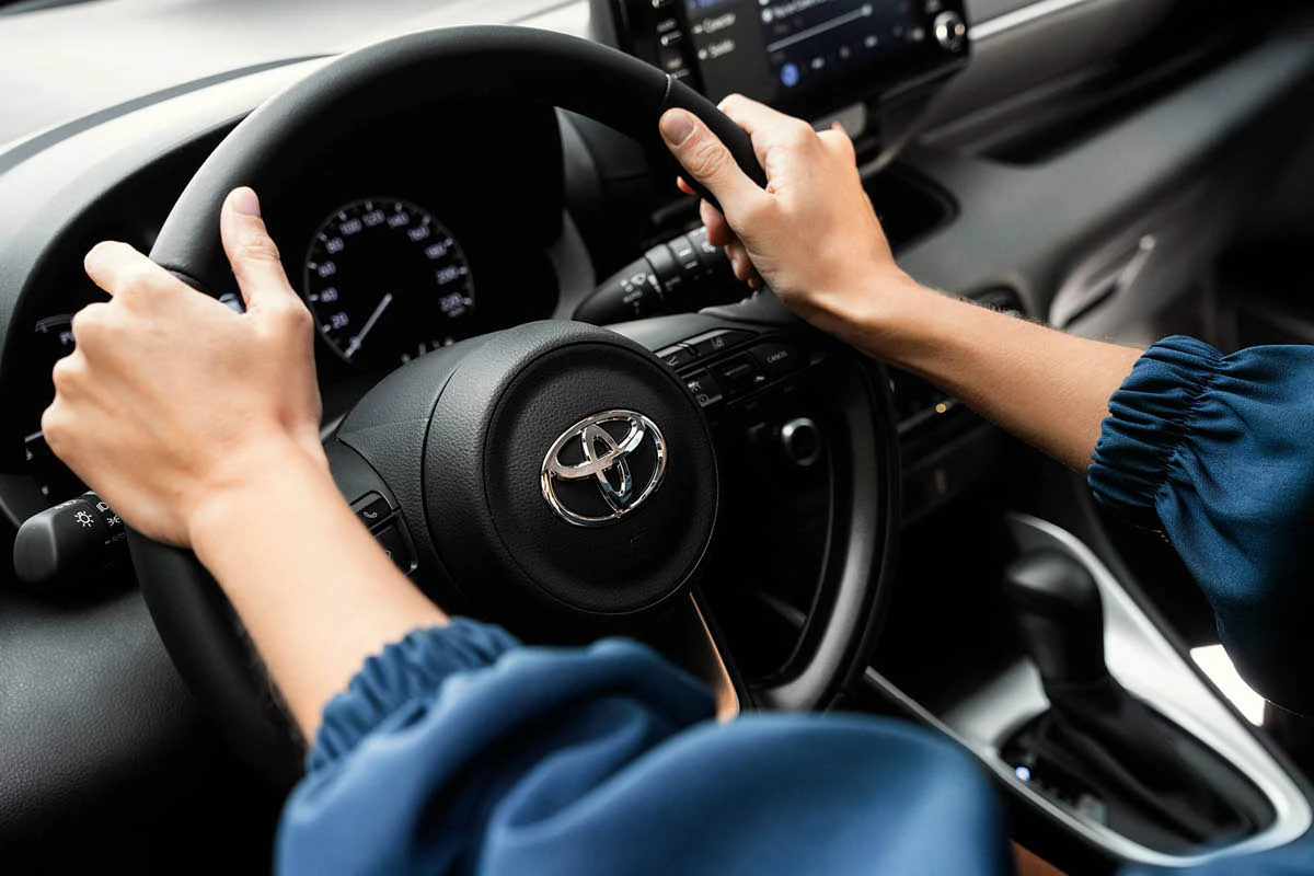 Ett par händer greppar ratten på en Toyota.