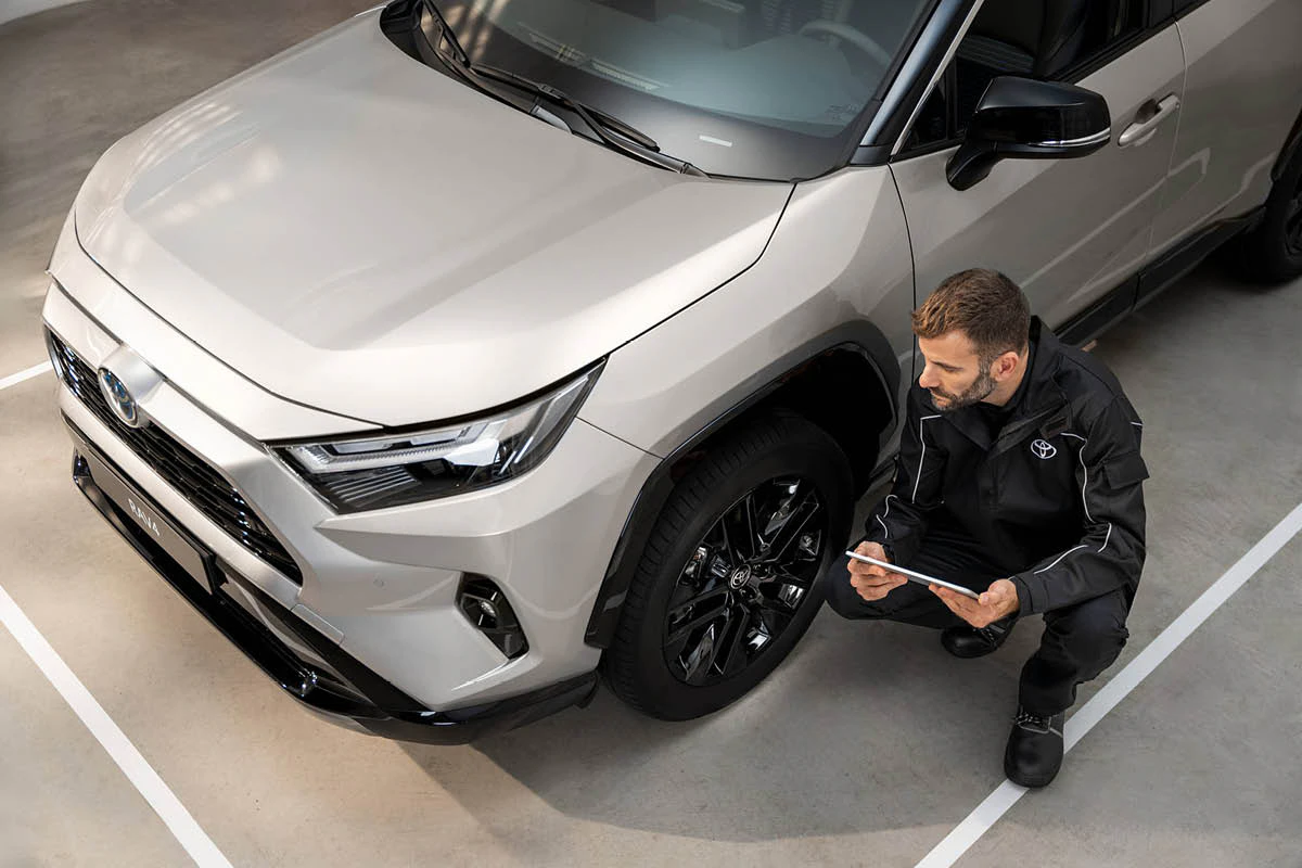 En tekniker tittar närmare på ett däck på en Toyota inför en däckbalansering.