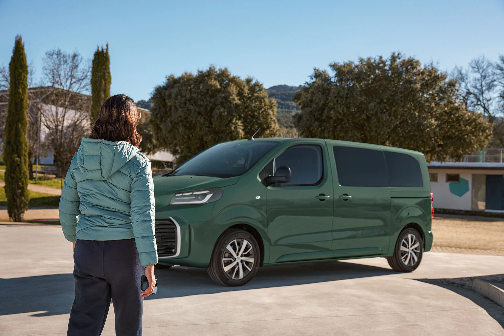 Kvinna går mot parkerad Proace Verso