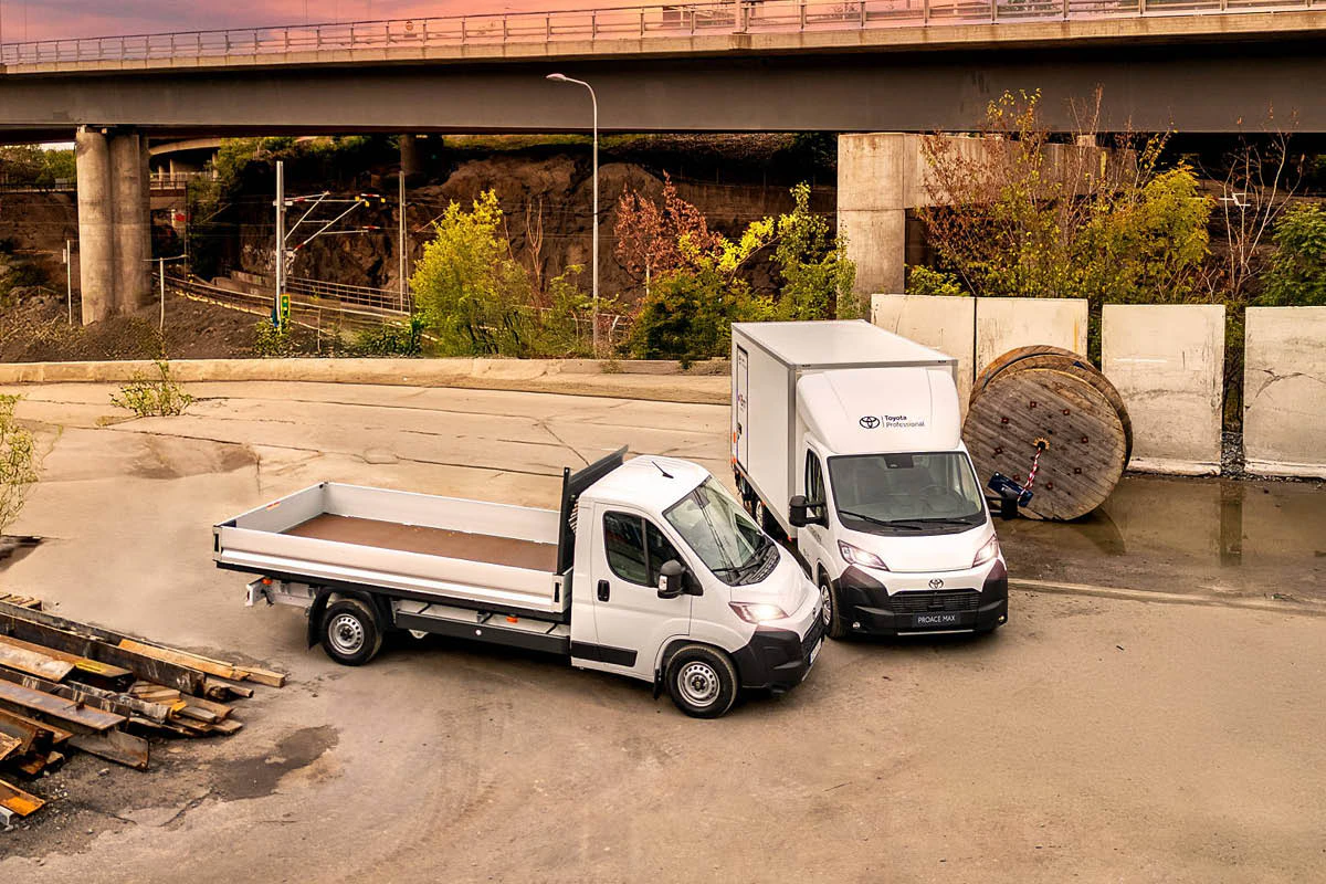 Två transportbilar från Toyota står parkerade vid en byggarbetsplats.