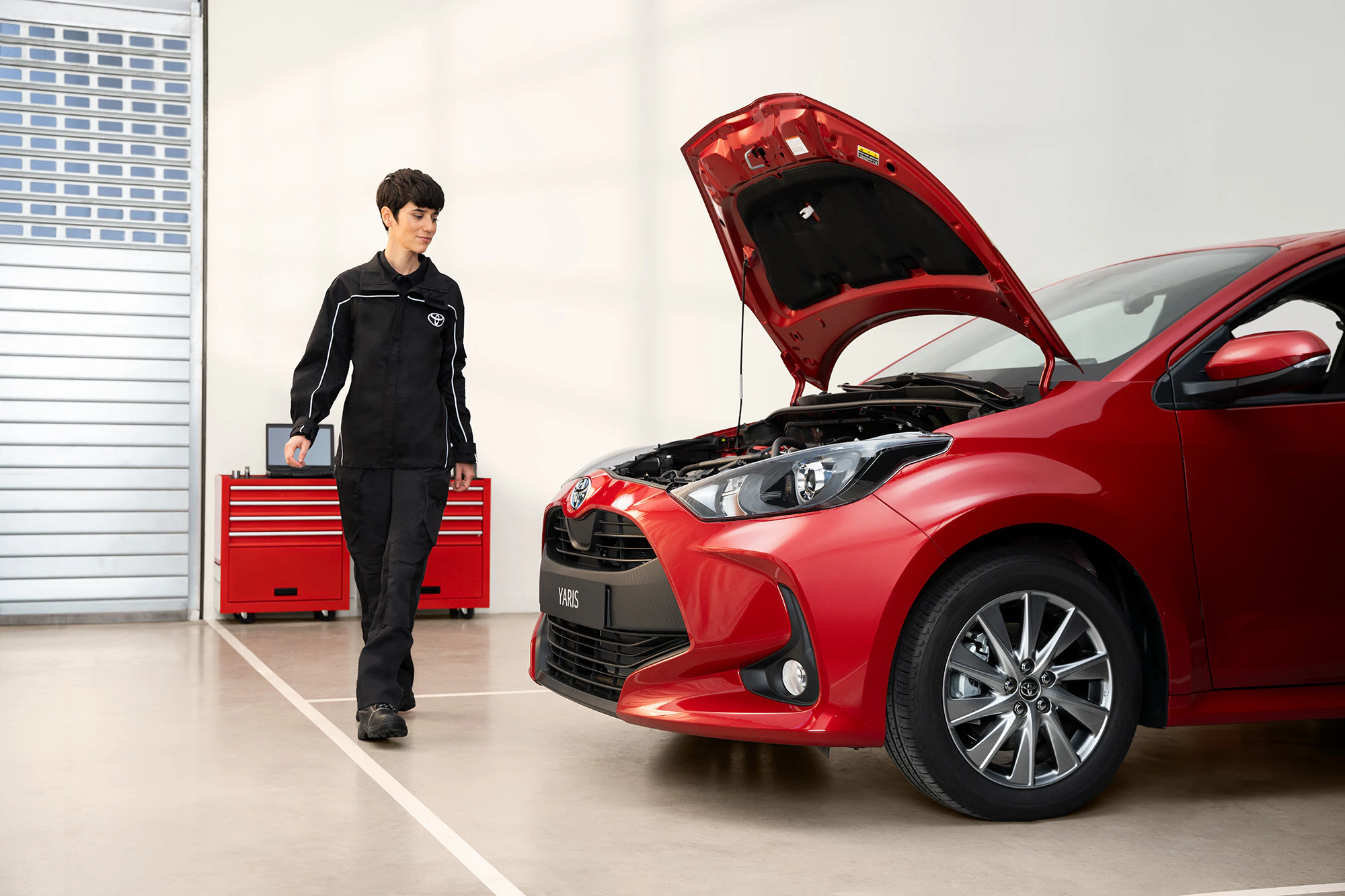 En servictekniker som utför service på en röd Toyota