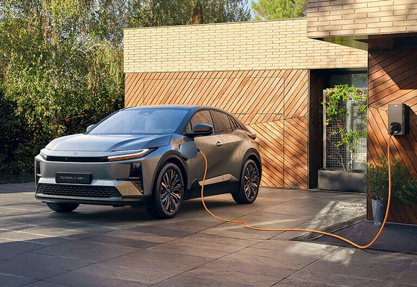 En parkerad Toyota laddhybrid i solsken vid en laddstolpe