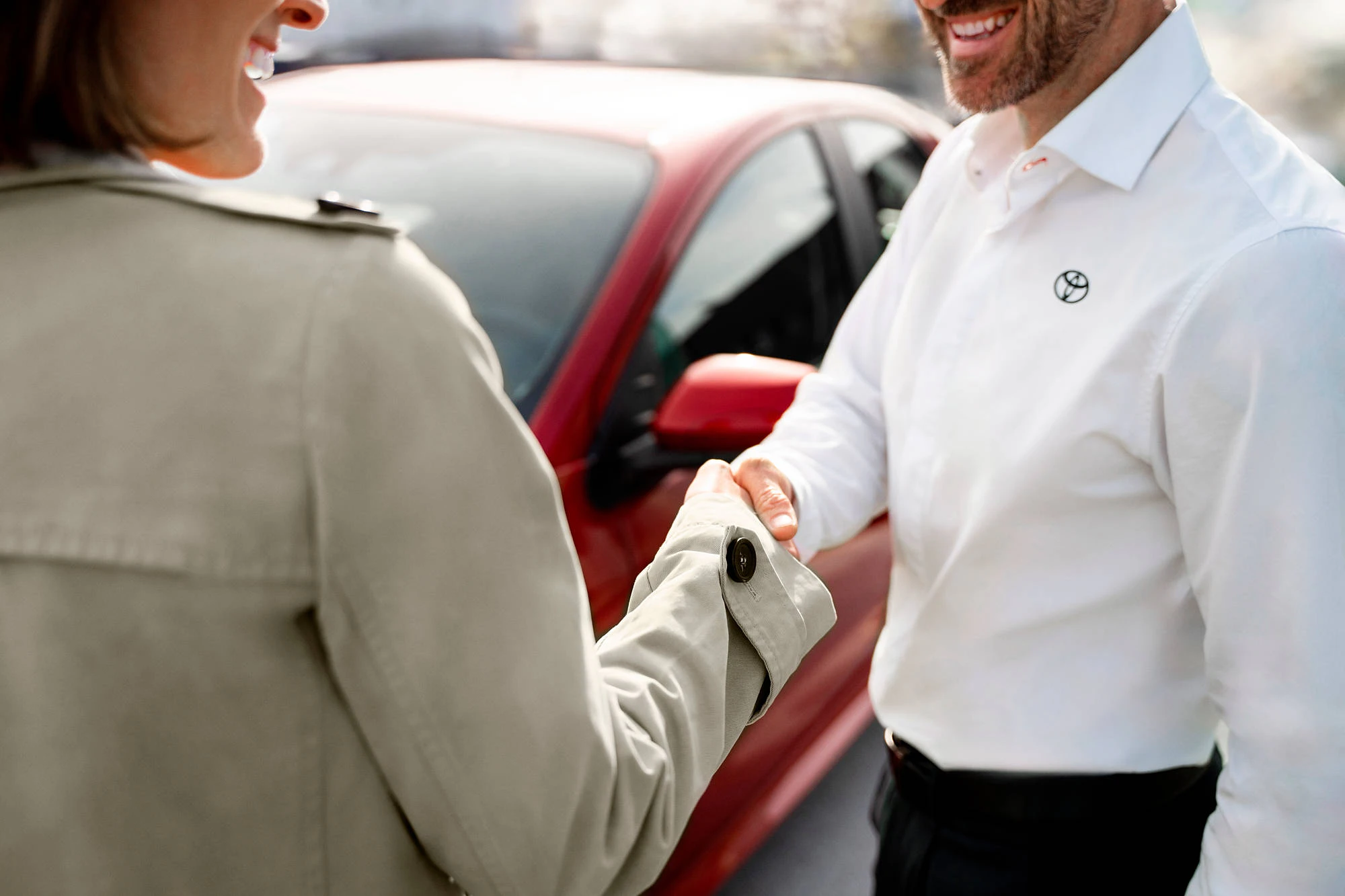 Man i skjorta med Toyota-logga skakar hand med kvinna