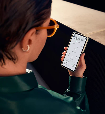 En kvinna som håller i en mobiltelefon med fjärrstyrda tjänster på skärmen