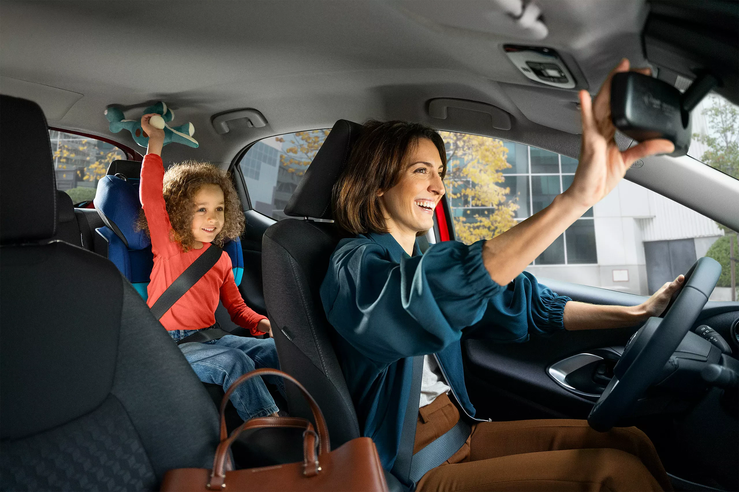 En glad famil i en Toyota bestående av en mamma vid ratten och ett barn i baksätet
